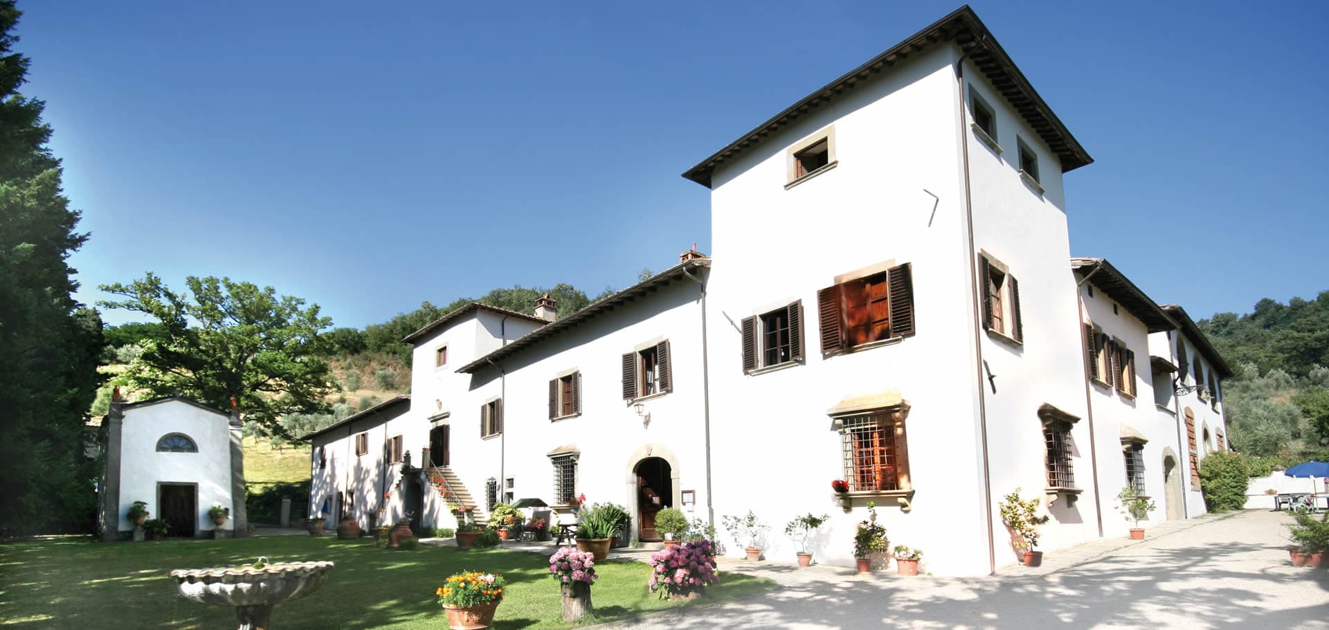 The long white facade of Villa Grassina with its gardens and the small chapel to one side