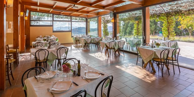 The estate restaurant, with tables laid in white linen under a beamed roof and glass walls onto the gardens